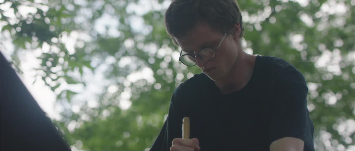A man stands outside moving a tool with his hand