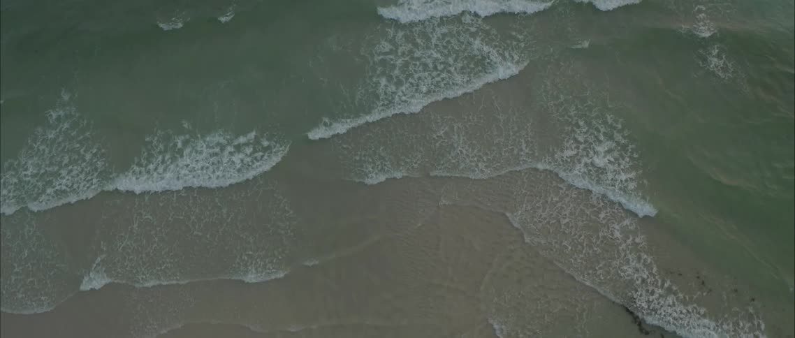 Ocean waves moving against shoreline of sand