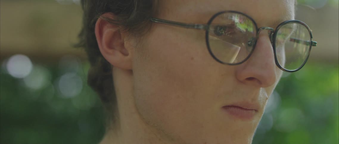 Person wearing glasses stands outdoors