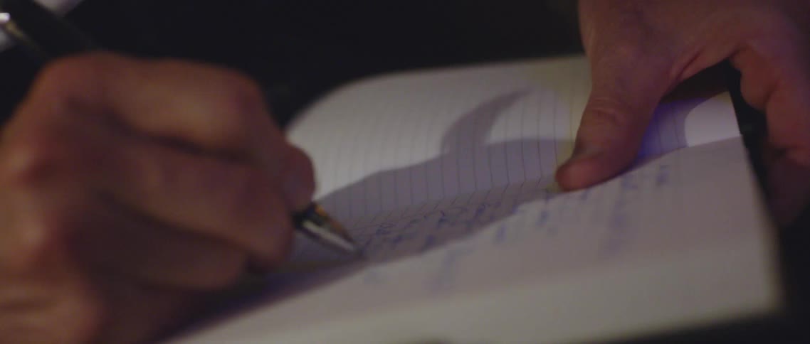 A person with a pen writing on a notebook