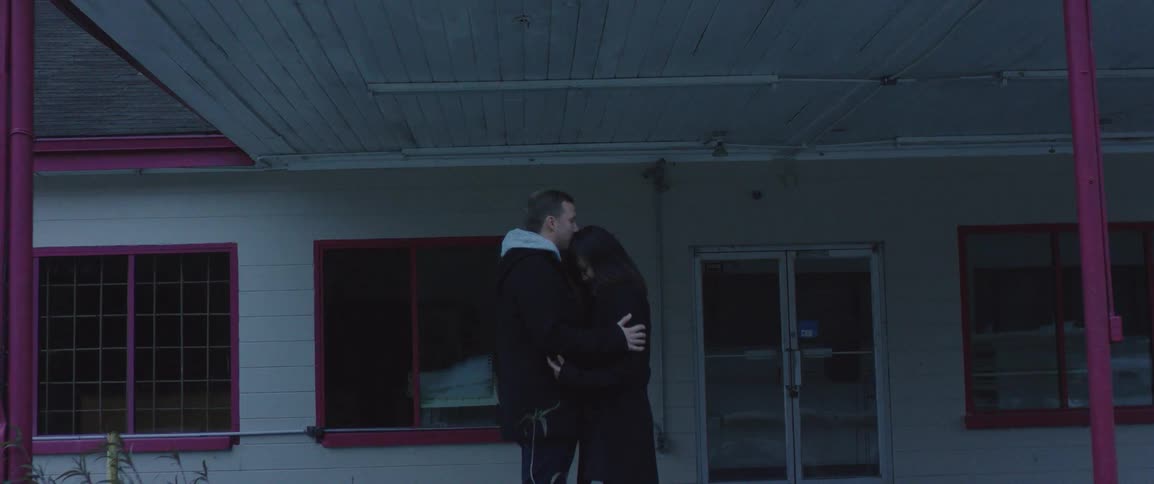 A man and woman hug outside a train depot