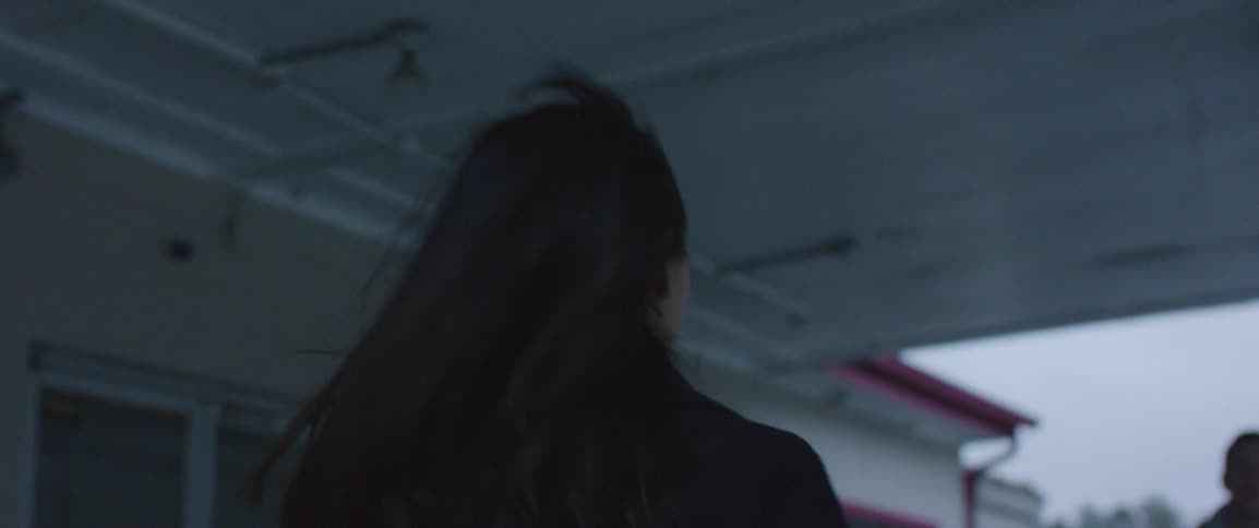 A woman runs past a train depot and into the arms of a smiling friend