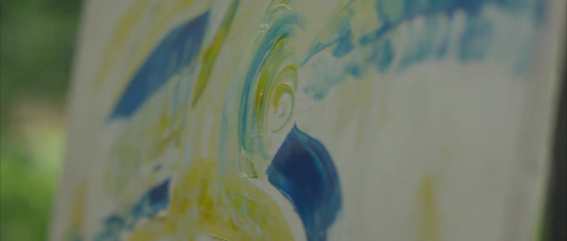 A person paints on a canvas outside