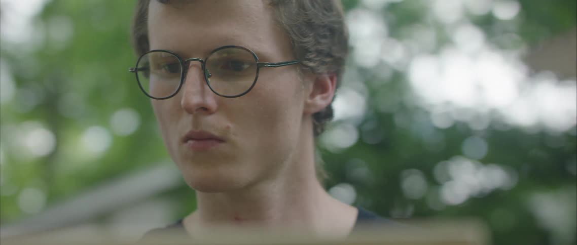 A young man stands outside and looks ahead of him