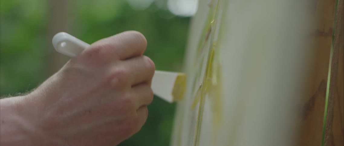 Young man uses a spatula to paint with oil over canvas in an easel outdoors