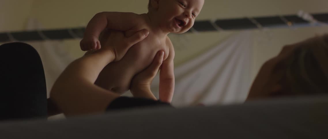 A mother holding and lifting a smiling baby