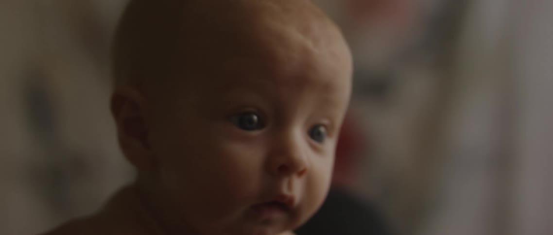 A baby laughs as its lifted up and down by a parent laying down