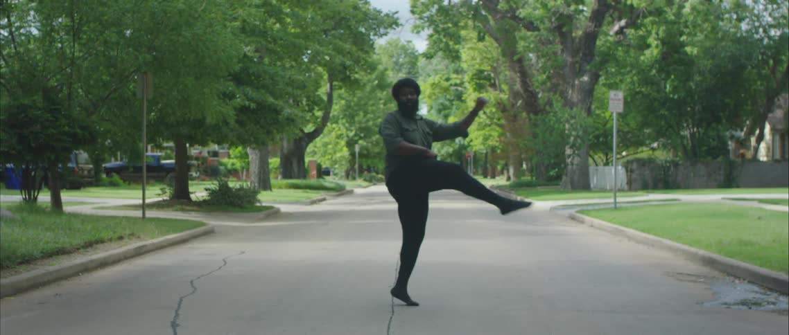 A man dancing in a street of a neighborhood