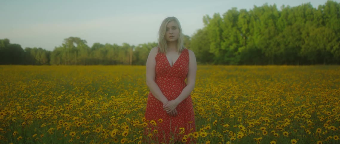 A young woman stands in a field of flowers