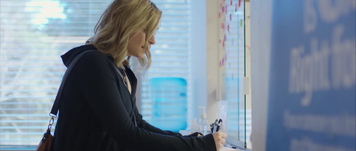 A pregnant woman uses a pen to sign in at a doctors office