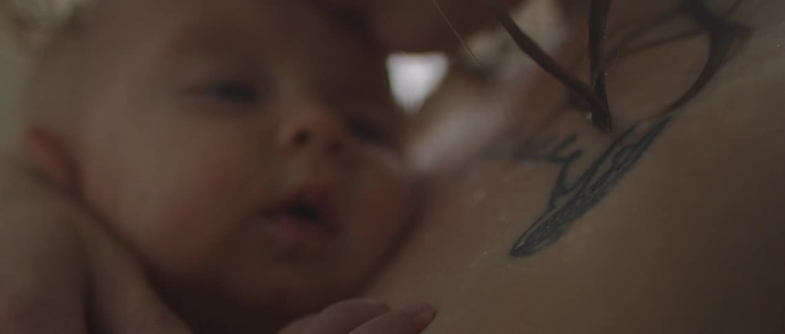 Baby resting over the chest of her mother in the shower at home