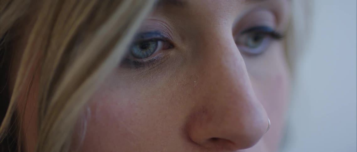 A womans face with green eyes eyeliner and a nose ring
