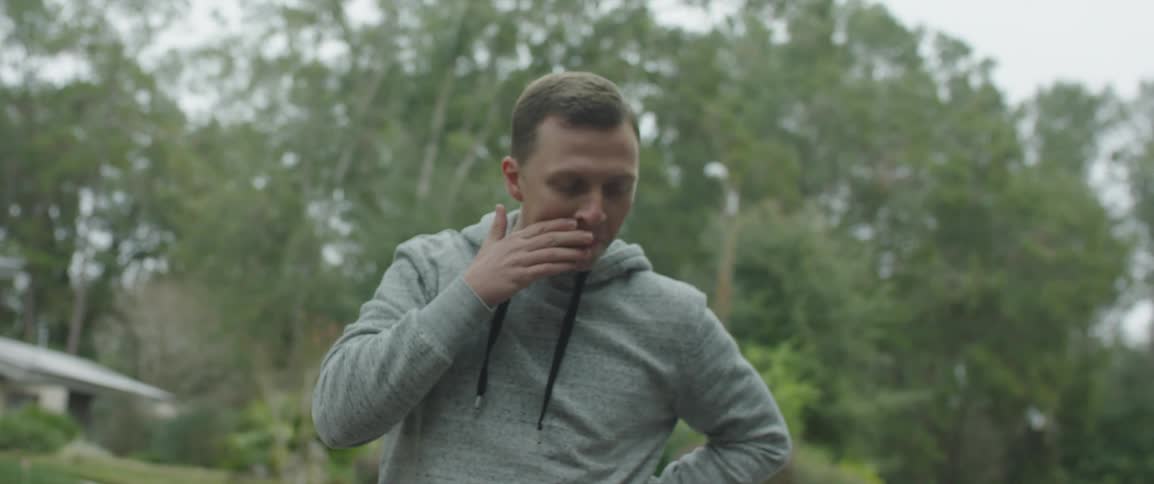 Man wearing hoodie walks through neighborhood breathing deeply