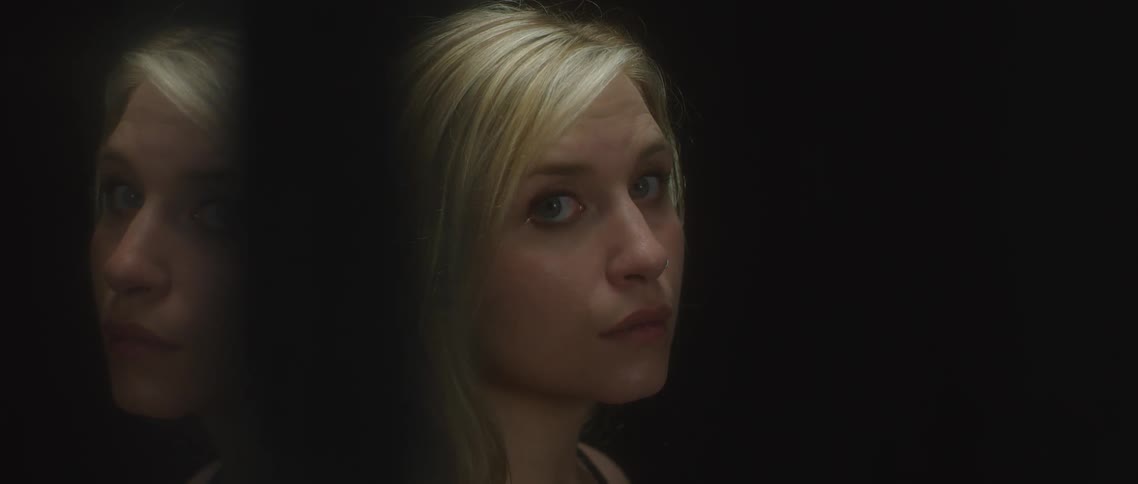 A blonde woman is in semi profile looking to her right