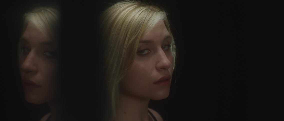 A woman is standing indoors by a wall