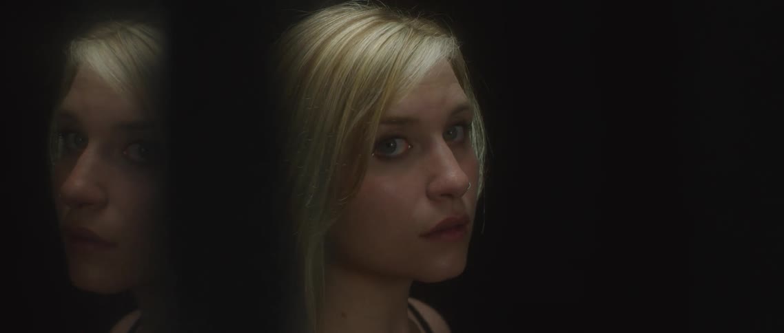 A woman standing in a corner while a light focuses on her