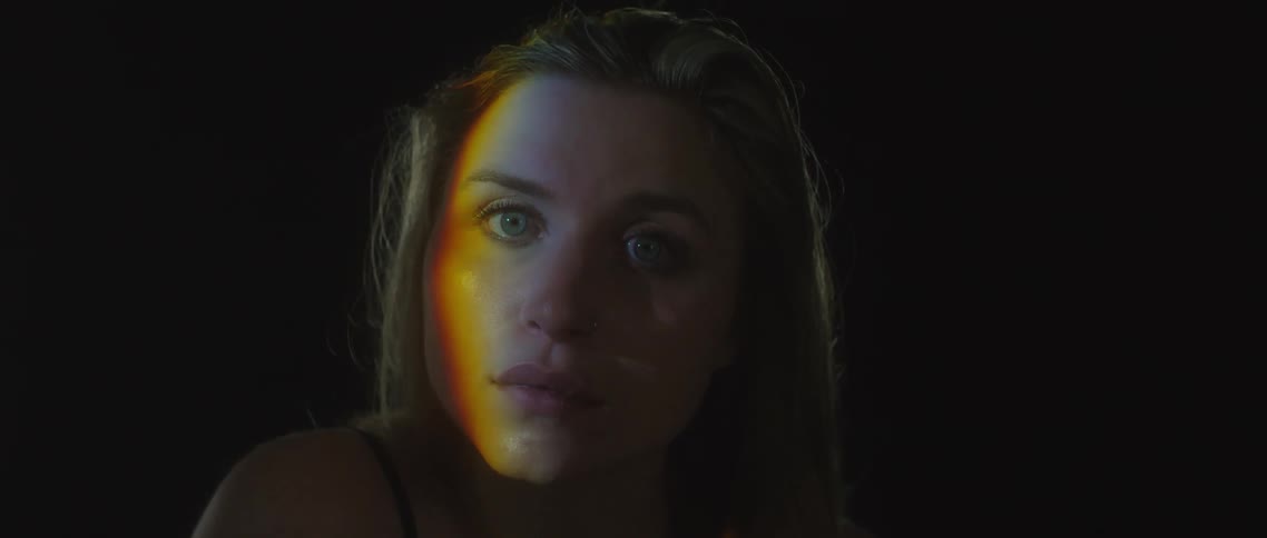 Young blonde woman looking at the camera inside a dark room