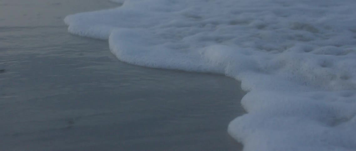 A sandy beach with water washing up on shore