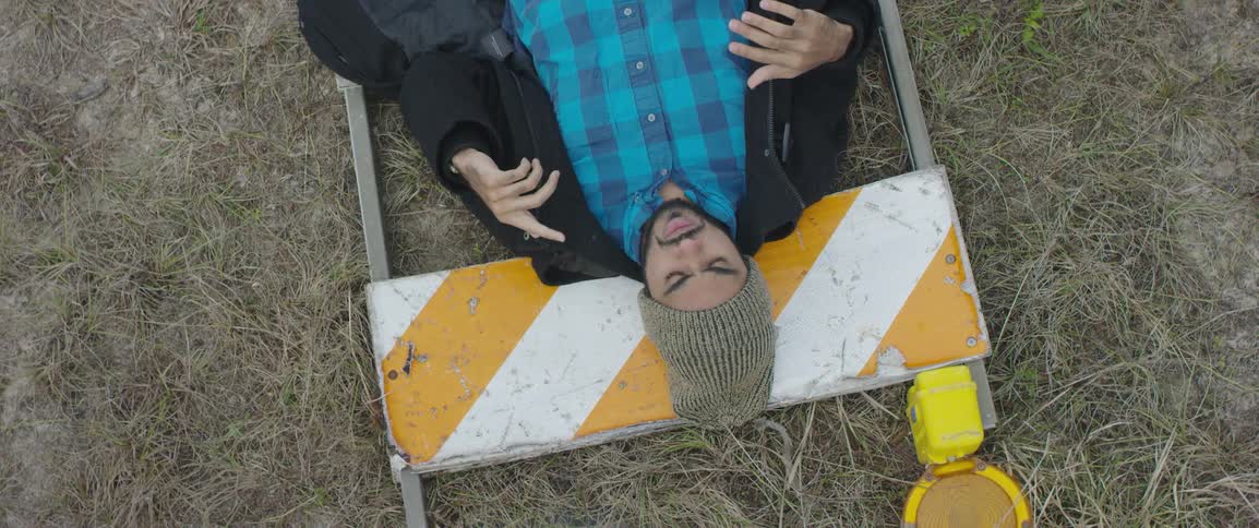 A man with a hat and jacket laying down on a sign on the ground