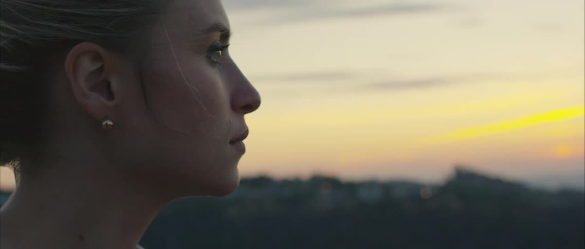 Woman stands outdoors at sunset