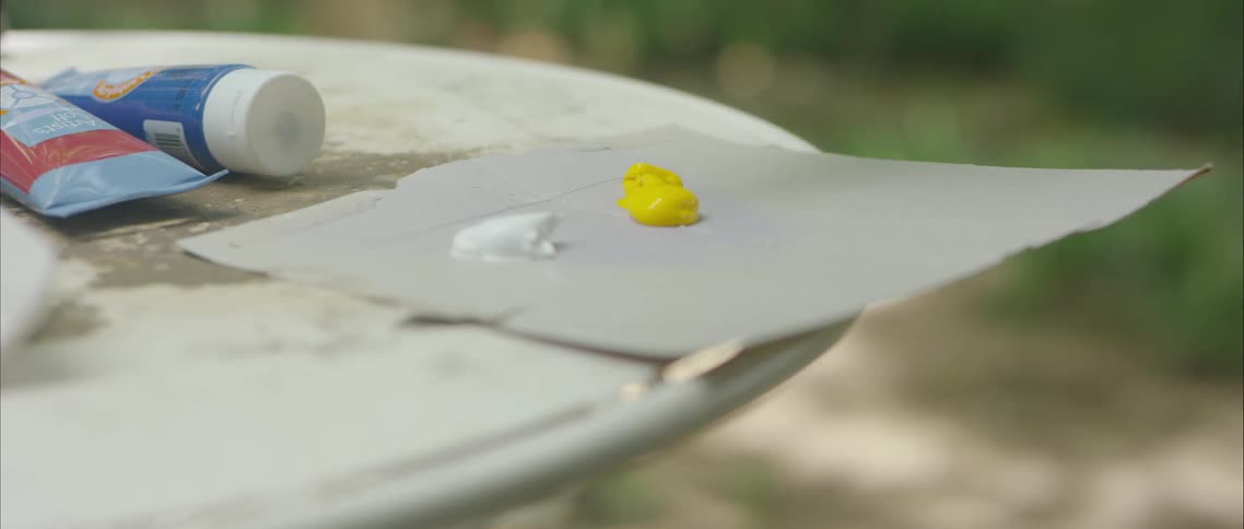 A person outside puts paint on a piece of cardboard