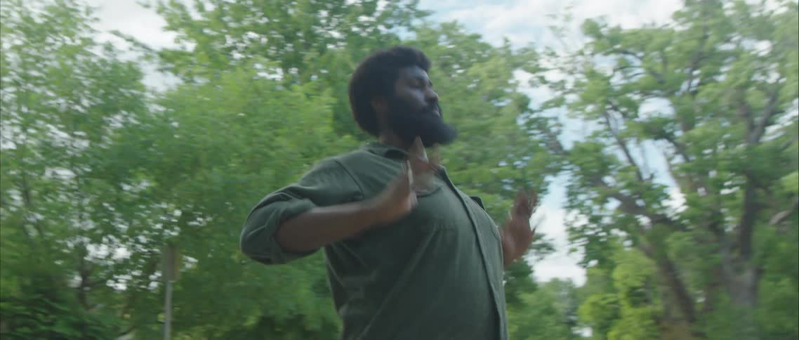 A man dancing on a residential street on a summer day