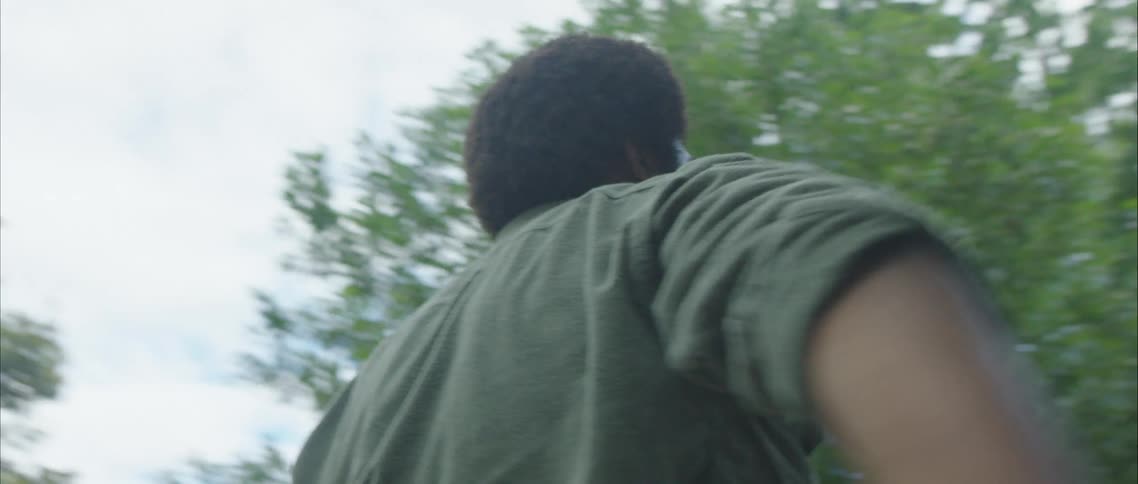 A man stands outside in a neighborhood performing a solo dance