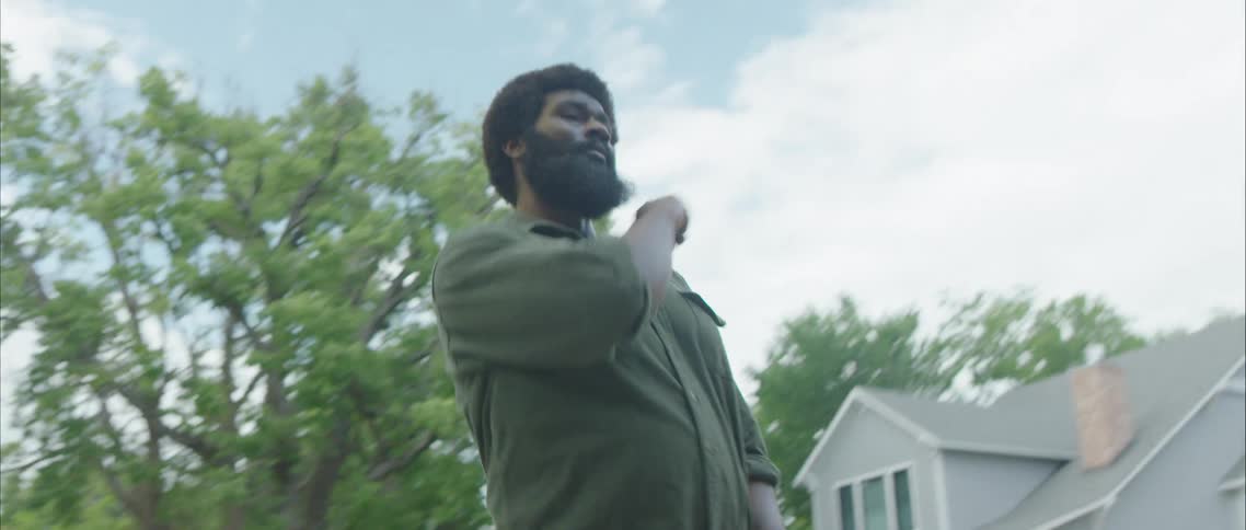 A man dancing in the street with houses trees the sky and clouds in the background