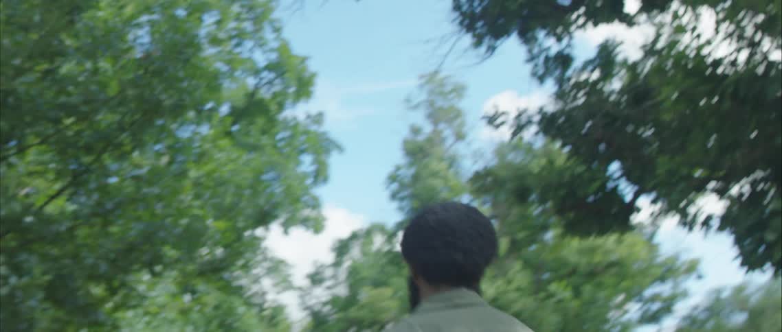 A man dancing in the street with houses trees the sky and clouds in the background