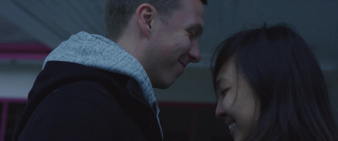 Young couple smiling at each other in a cold day near a house at day time