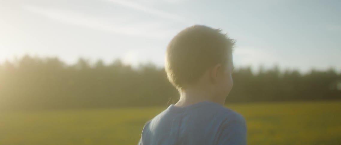 A boy runs through a vast field on a sunny day