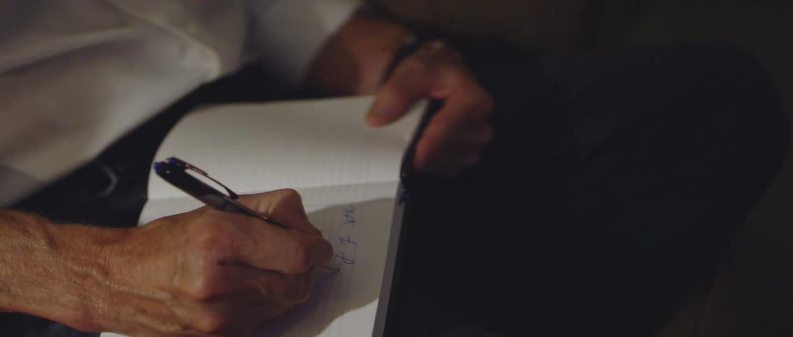 A man writes in a notebook