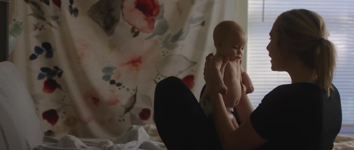 Mother holds her baby in her lap talking with her