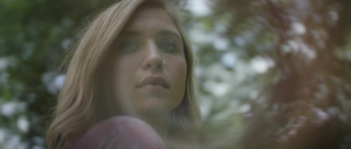 Young blonde woman turns around to look at the camera in the forest