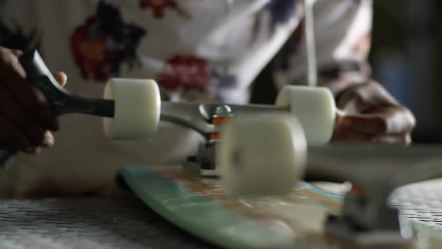 Girl adjusts white skateboard wheel sitting on table