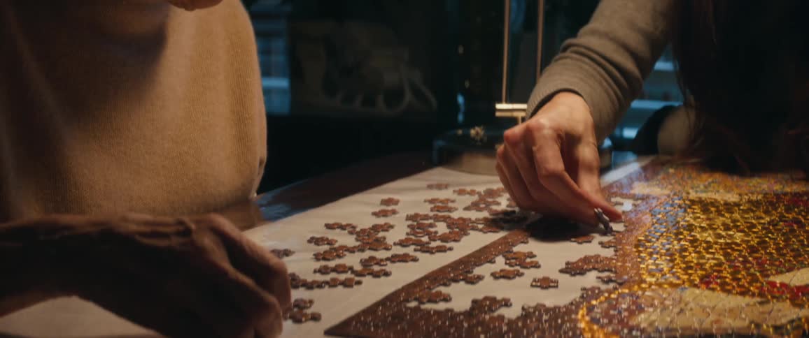 Elderly woman and daughter put together jigsaw puzzle sitting at table