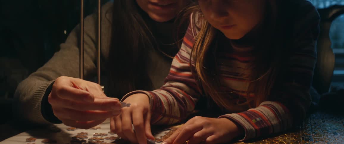 A mother daughter and grandmother doing a puzzle together at a table