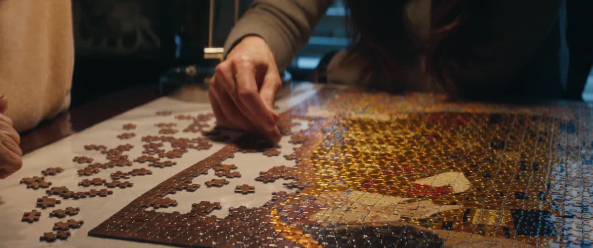 A couple of friends solving a jigzaw puzzle over a table at home