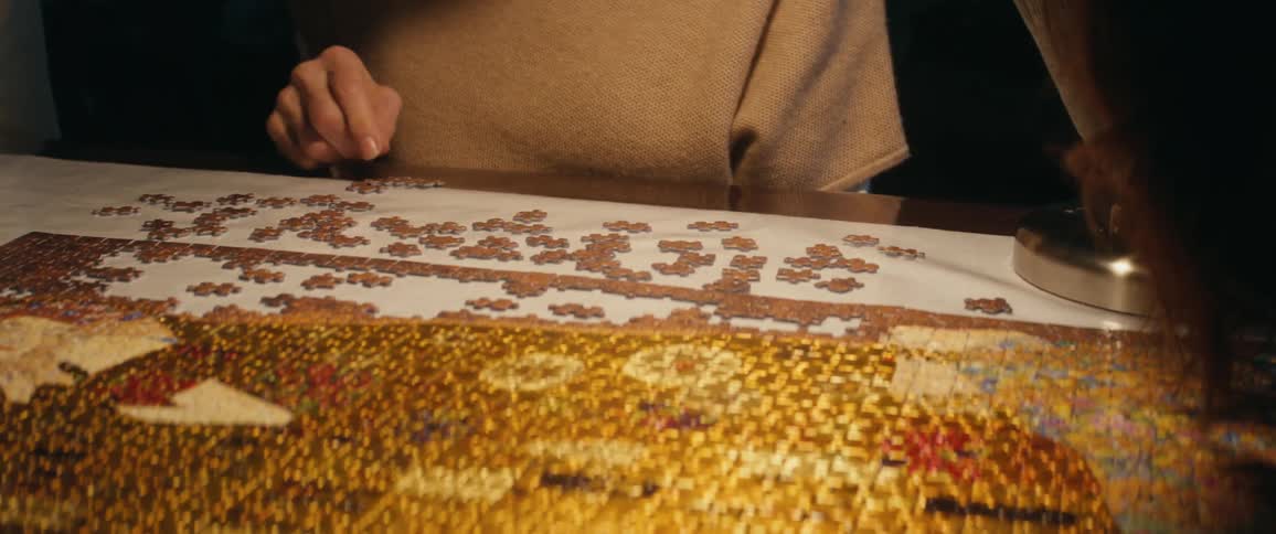 Two women look at puzzle pieces while sitting at a table