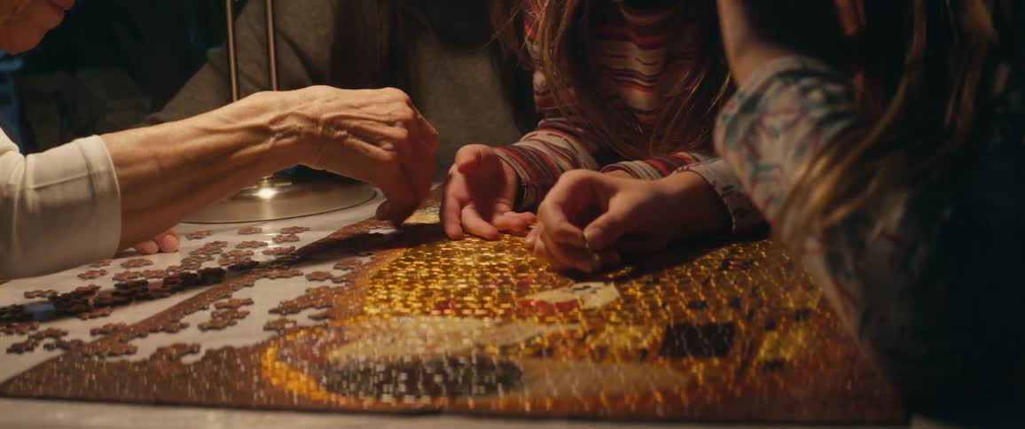 Two female children and two female adults work on a jigsaw puzzle