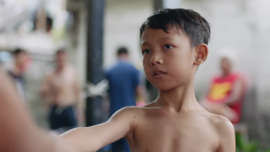 A man wraps tape on a small boys arms before he participates in his sport