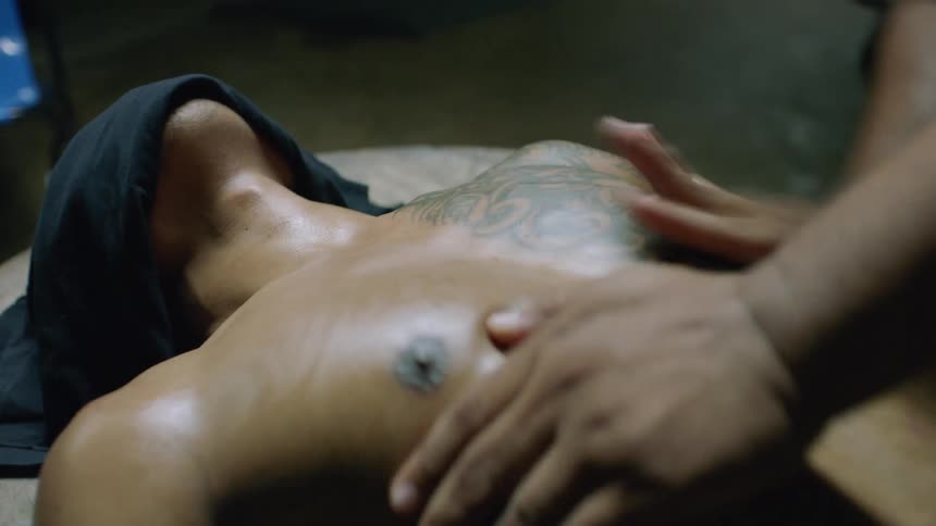 A fighter lying on a table with a towel on his face receives a chest massage from a masseuse