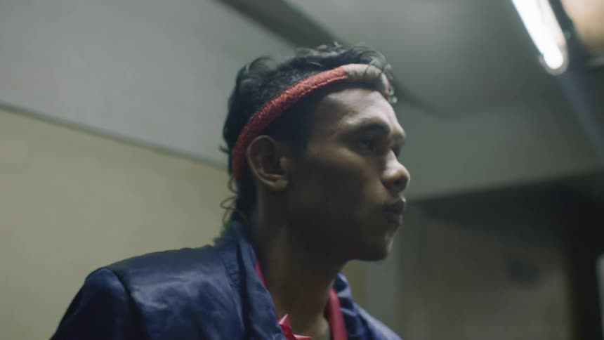 Man wearing headband and jacket moves and takes deep breath while waiting in hall