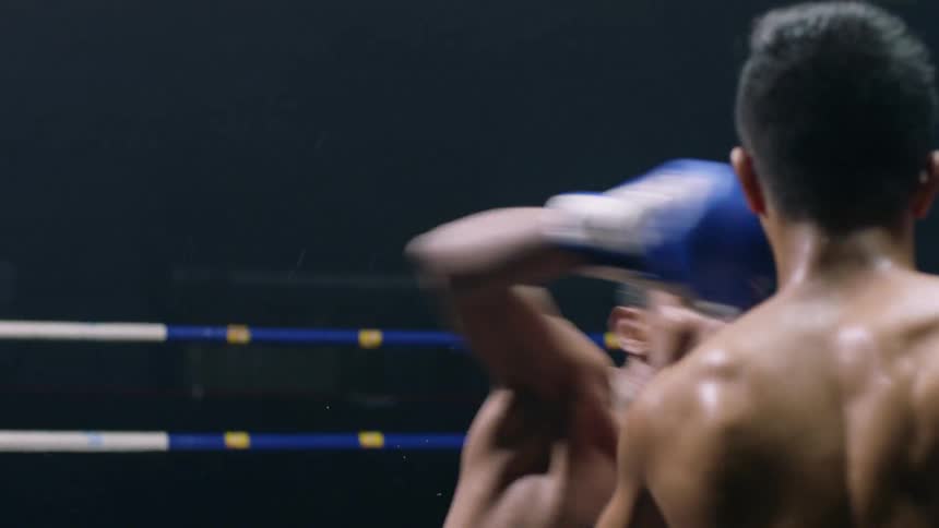 A boxer punches and knocks out his competitor in a boxing ring