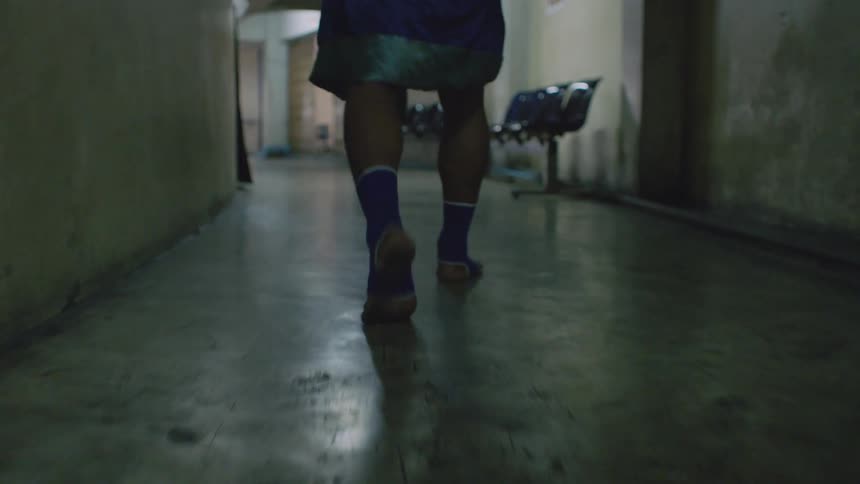 Man wearing a robe and socks walks down a hallway and starts to run