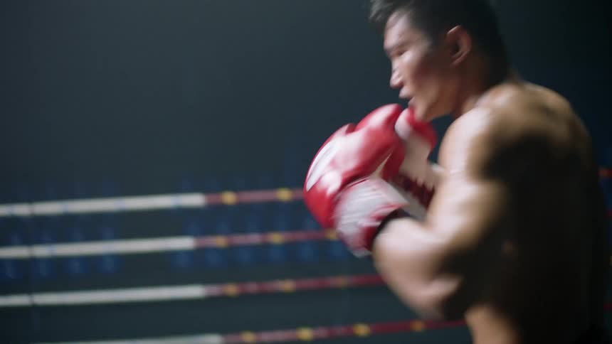 Two boxers box in ring in dark area