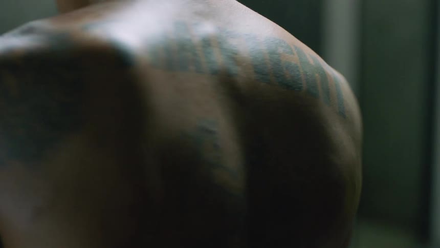 Boxer wearing yellow gloves with tattooed back stretches and flexes warming up