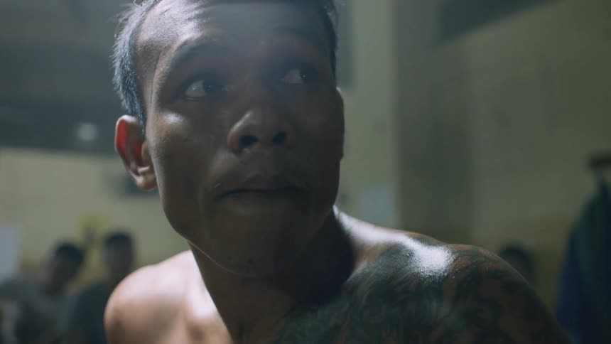 A nervous boxer with tattoos fidgeting while shirtless