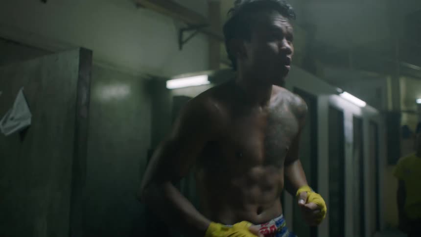 A man practices boxing in a room with people milling around