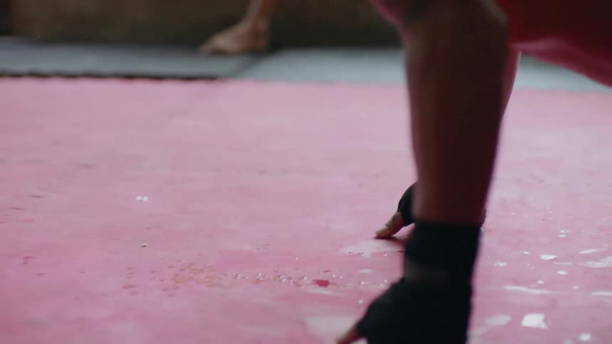 Young fit shirtless man doing push ups in a muay thai kick boxing gym